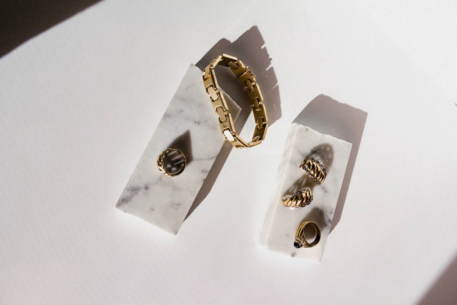 set of gold jewellery on a piece of marble with a white background
