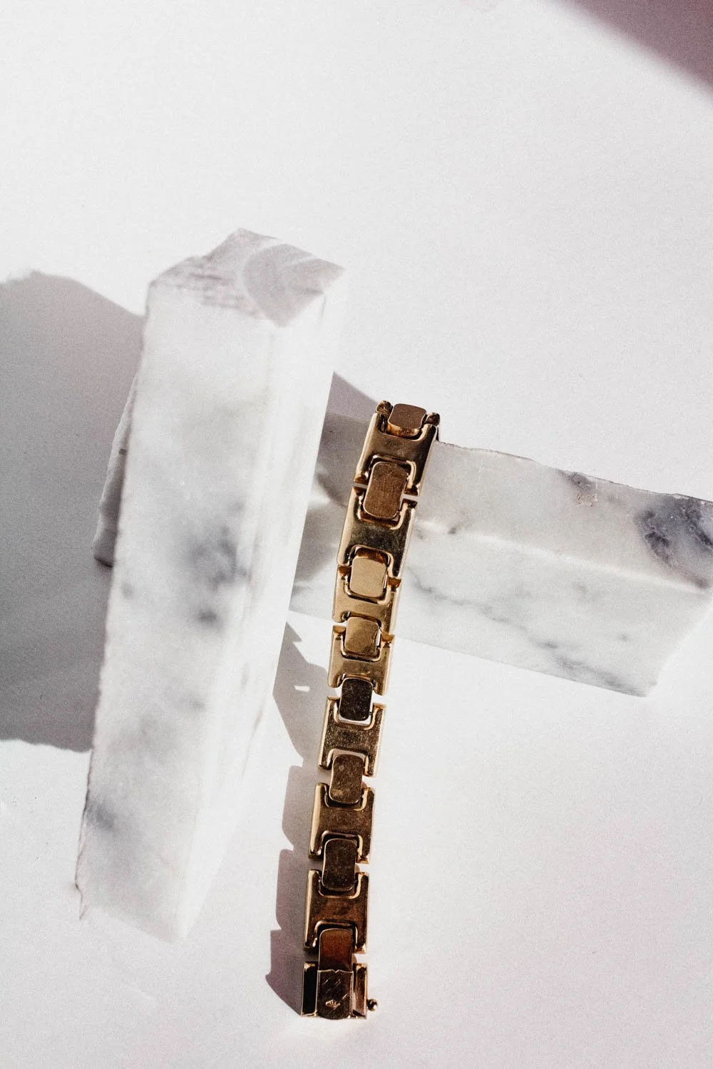 gold bracelet on marble pieces with a white background 