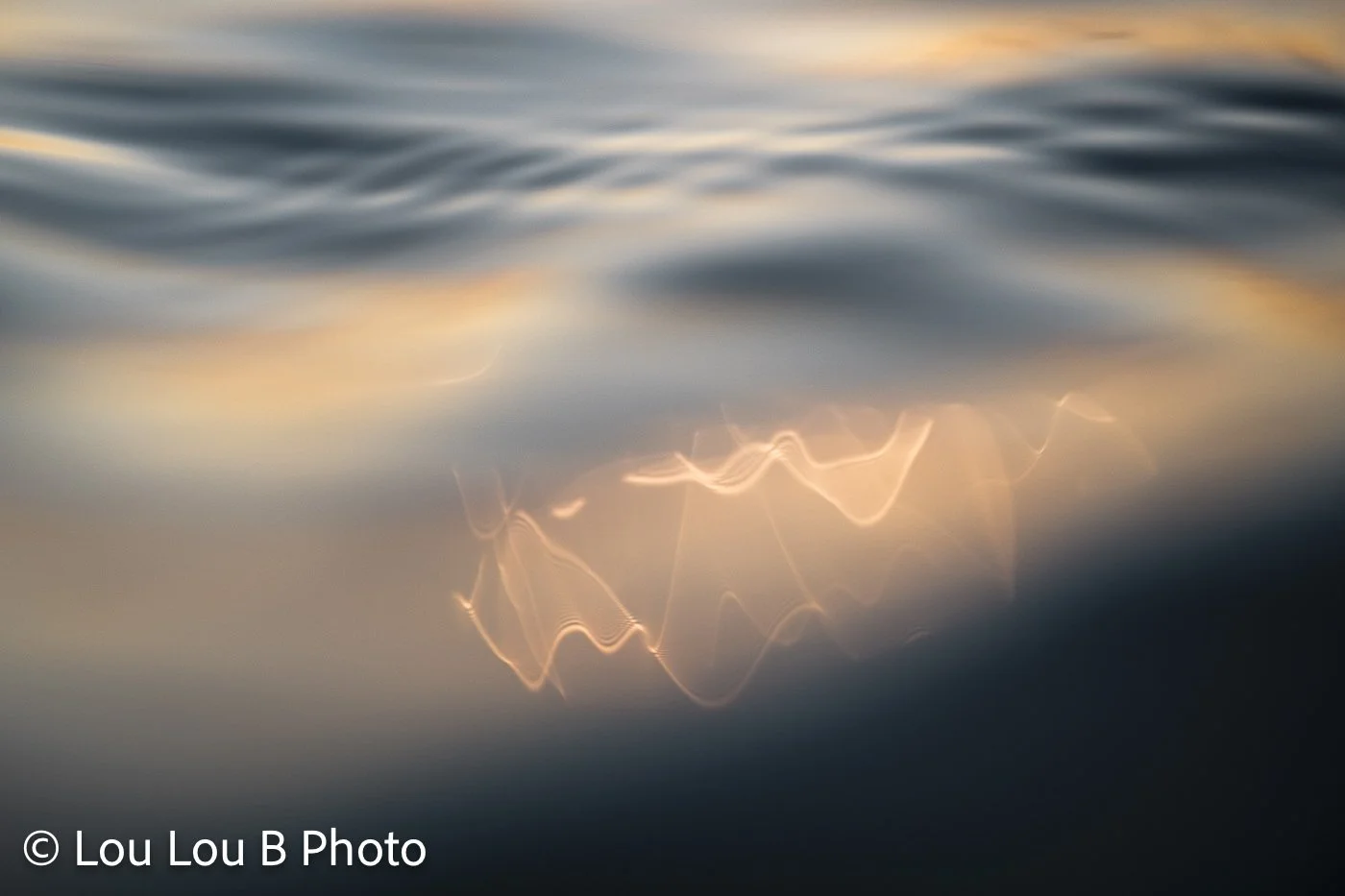 Abstract close-up of soft ocean ripples reflecting warm golden light.