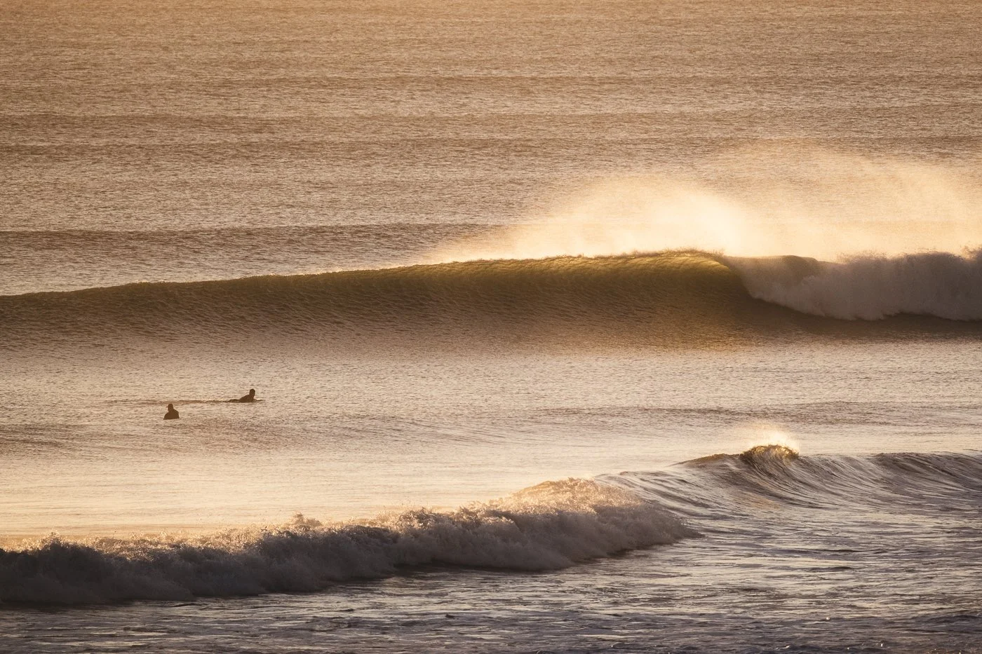Surf photography from shore capturing golden light on ocean waves at sunrise