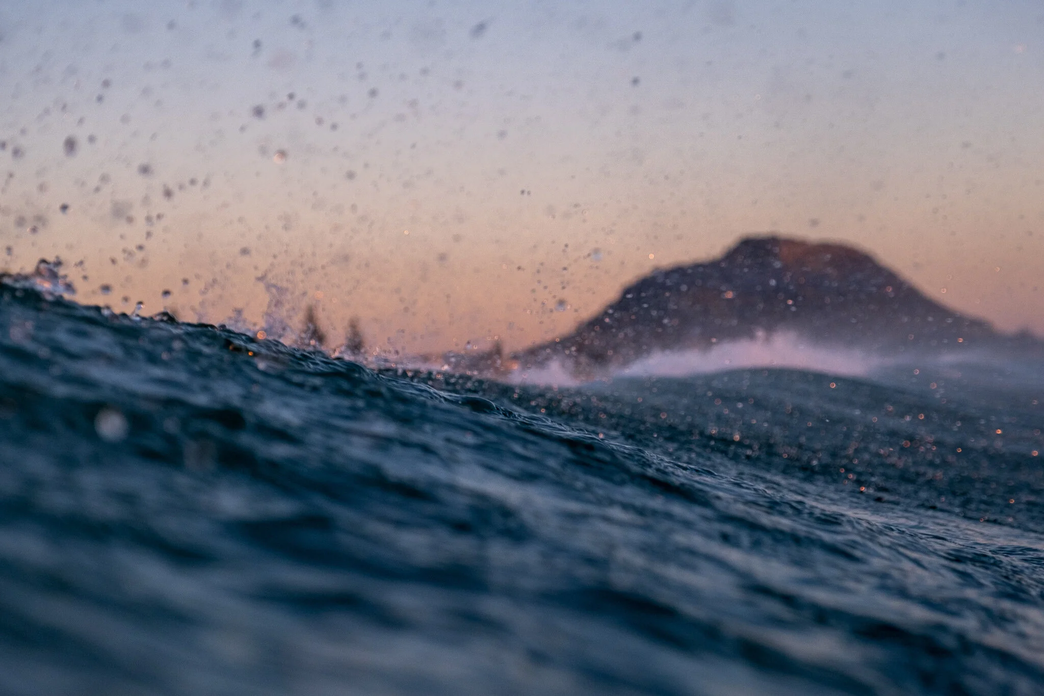 Sunrise behind the waves at Mount Maunganui, New Zealand with colourful droplets.