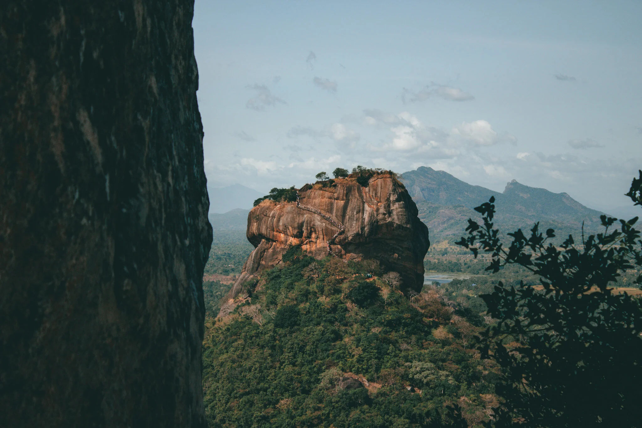 A stunning view of the ancient fortress of Sigiriya in Sri Lanka. The photo was taken from Little Sigiriya, providing a unique perspective of the impressive rock formation. The top of the fortress can be seen in the distance, surrounded by lush green