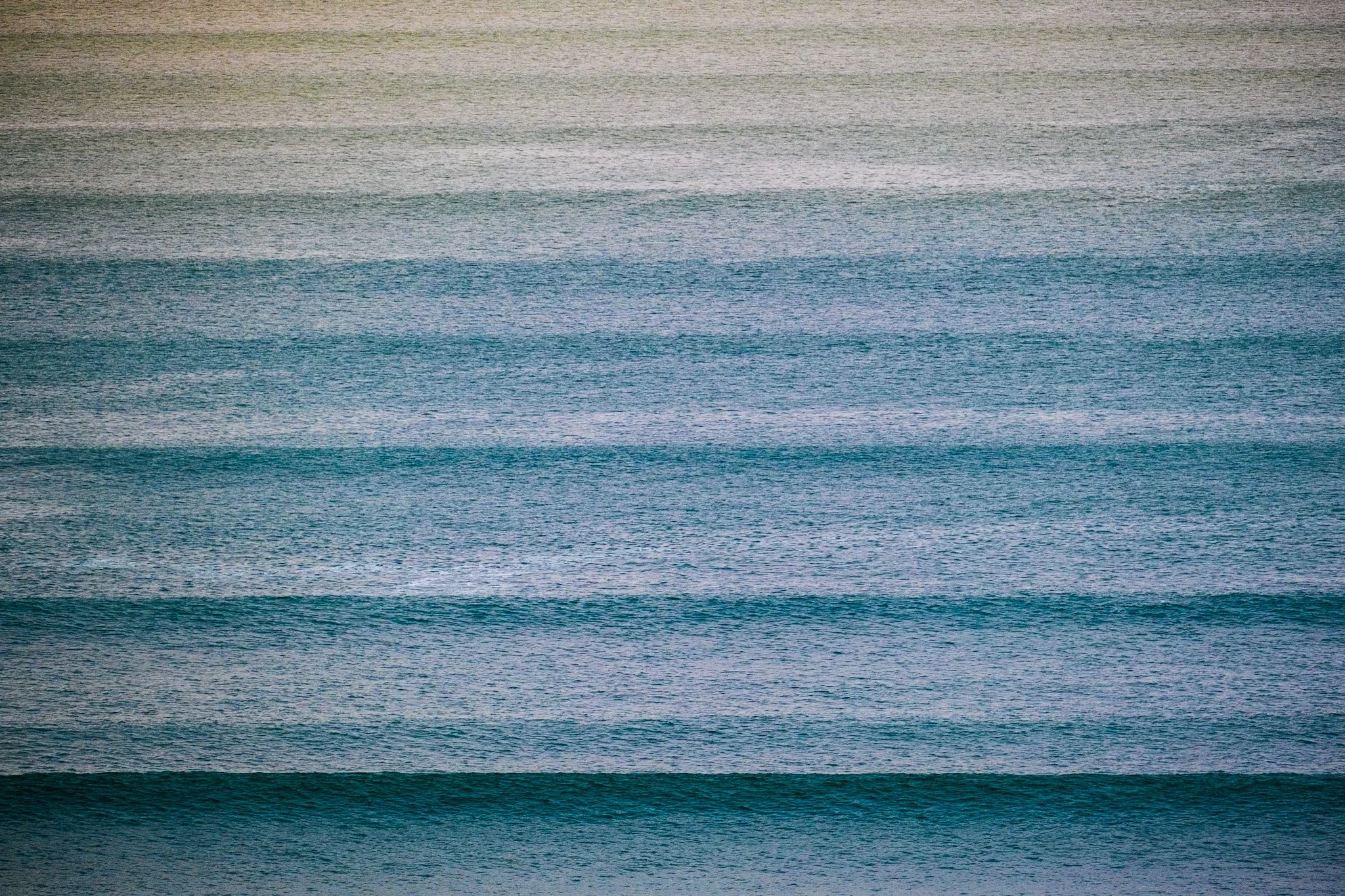 Waves line up on the horizon at sunrise, looking west towards Raglan, New Zealand. A breathtaking and awe-inspiring landscape view of the power of the ocean. A stunning surf lifestyle photo by Lou Lou B Photo.