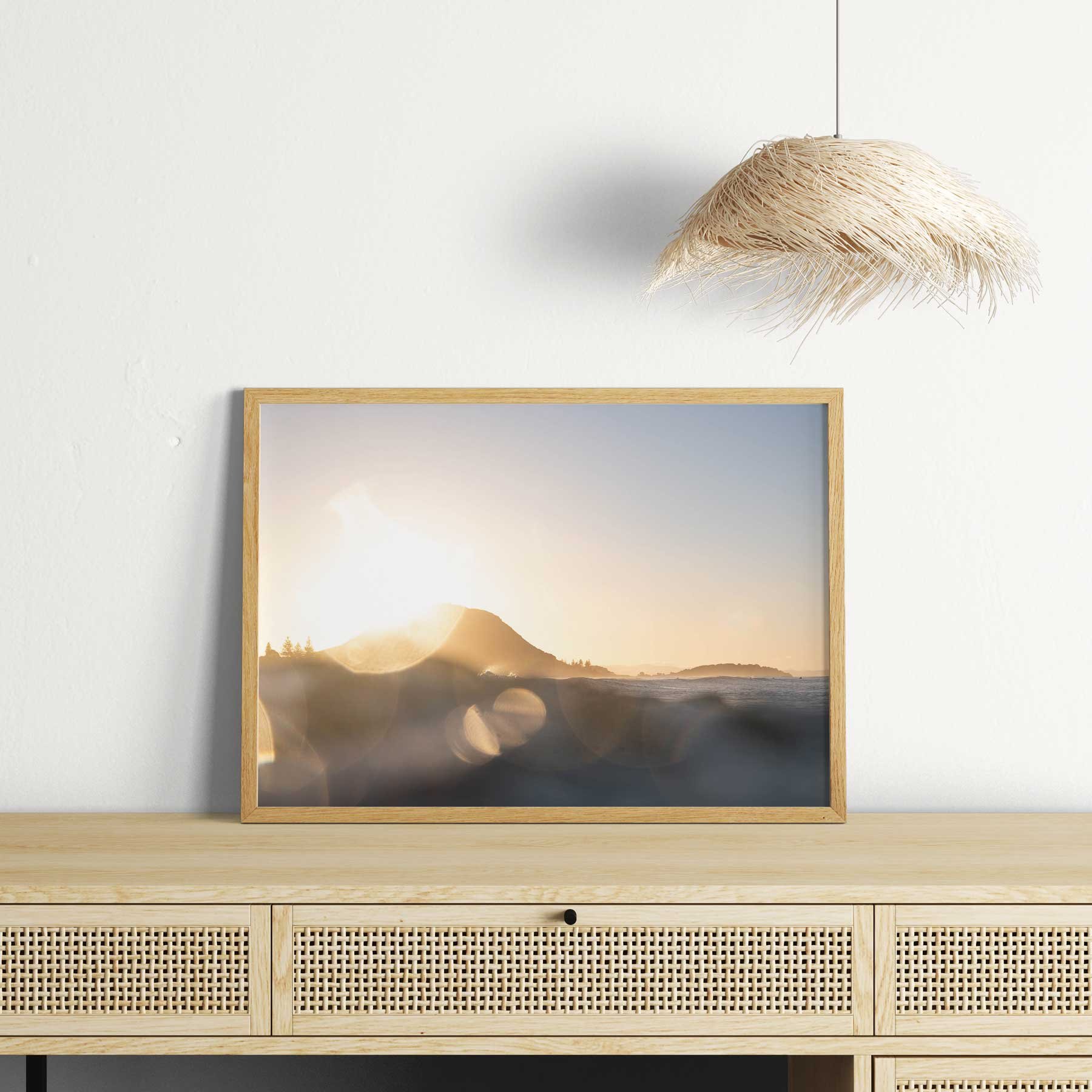 Fine art photographic print of Mount Maunganui at sunset, featuring bokeh of the golden light over the ocean styled in a frame in a boho coastal home.