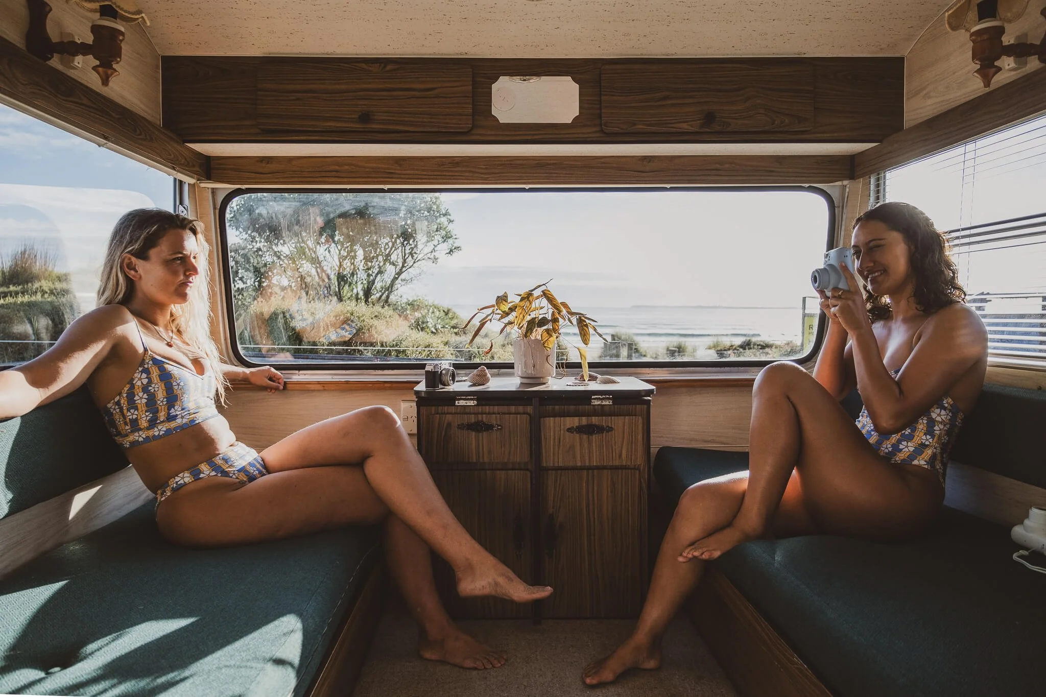 Surf lifestyle photo of two surfer girls in caravan and summer sunshine after a surf