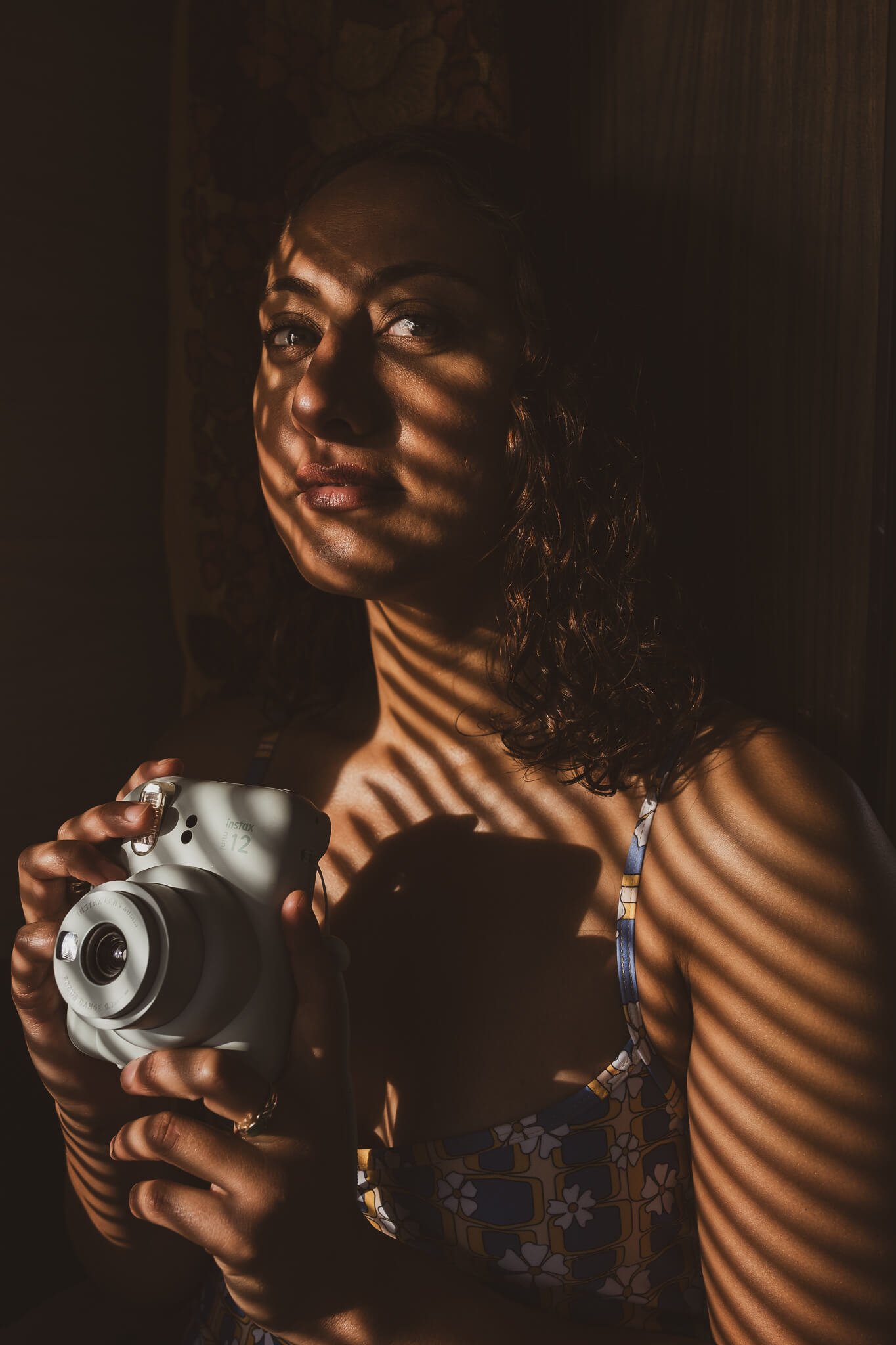 Female longboard surfer holding Fujifilm Instax camera after a surf