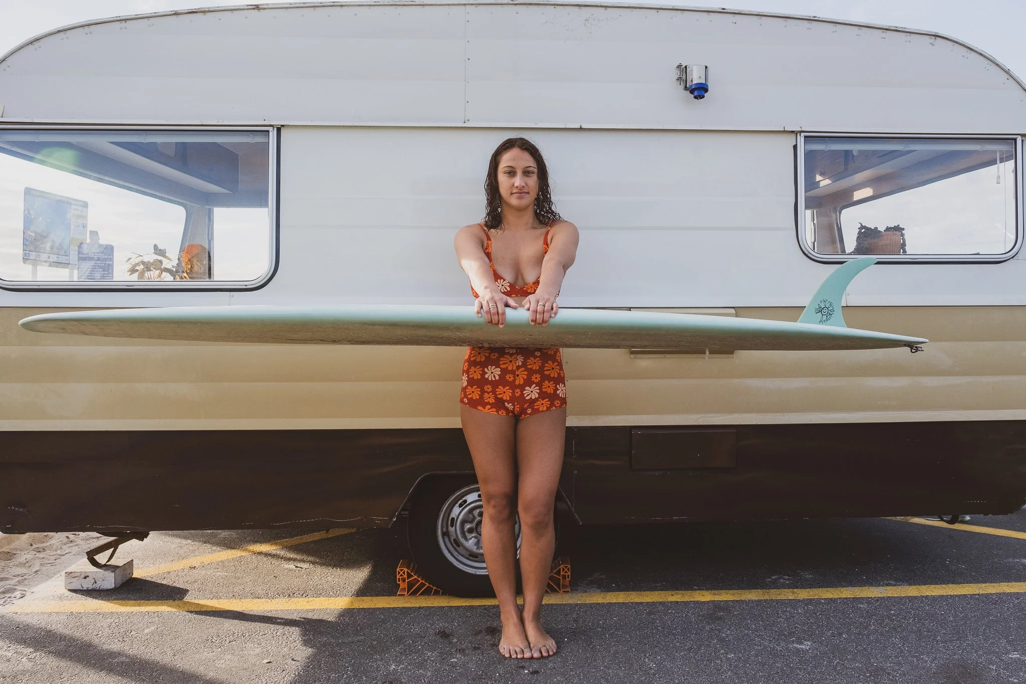  model standing beside retro surf caravan during nostalgic surf brand photography shoot inspired by mood board styling direction 