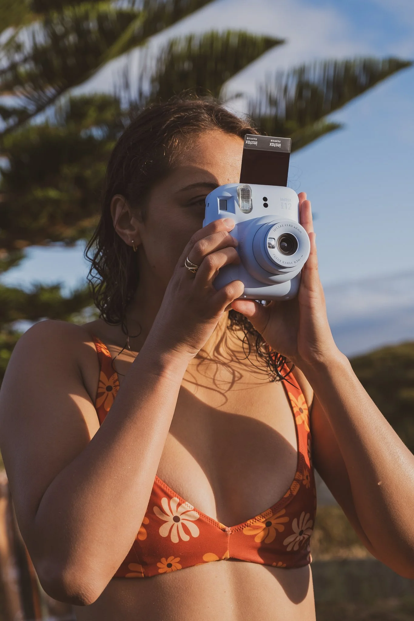  model using instant camera during nostalgic surf lifestyle brand photography shoot inspired by retro mood board references 