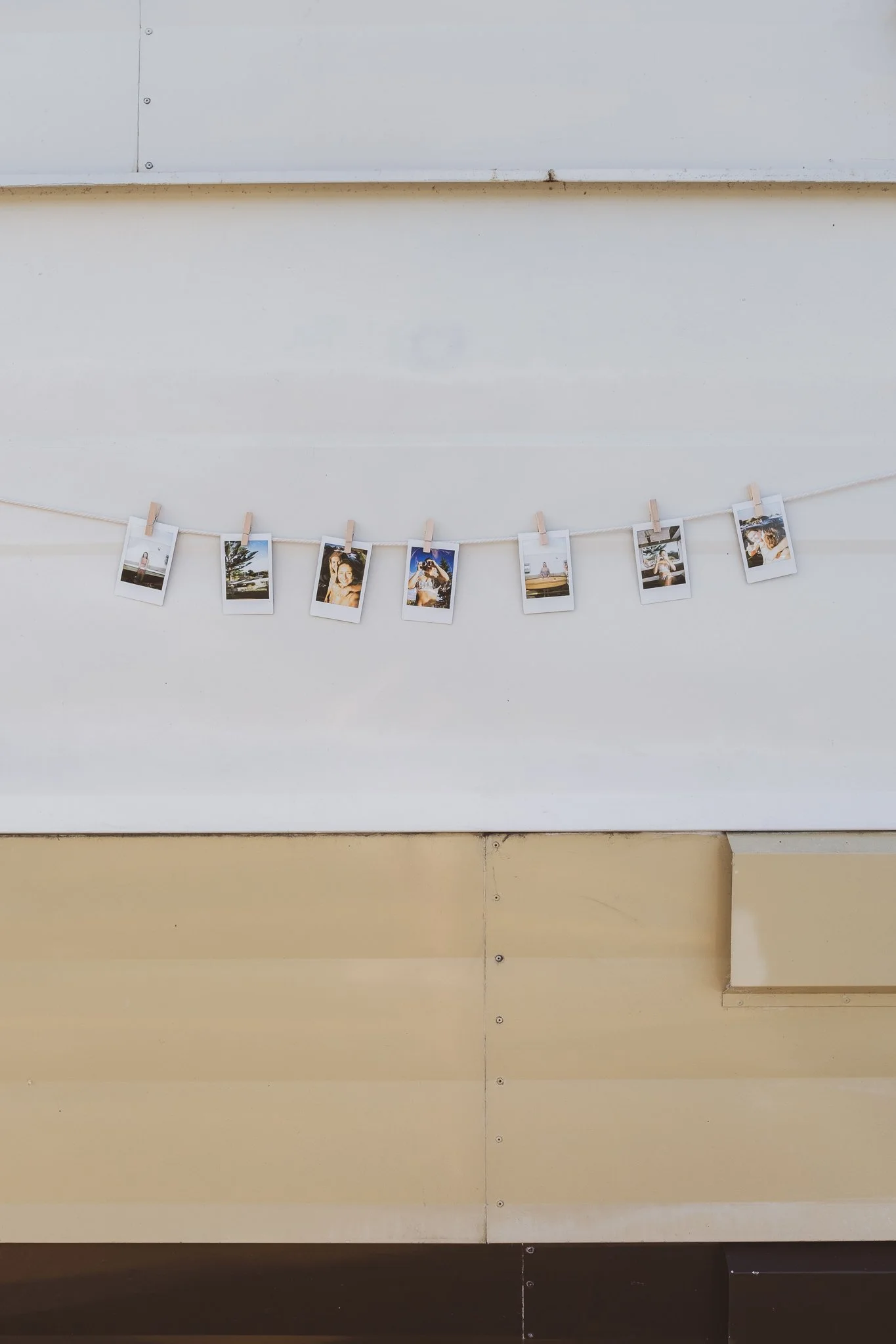  instant film photo prints hanging on caravan wall as styling detail in nostalgic surf brand photography shoot 