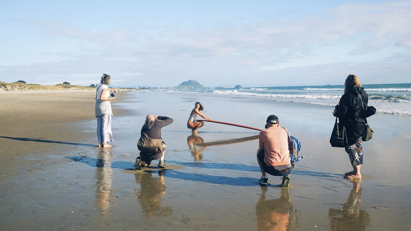 photographers shooting model with longboard during Nostalgic Surf styled surf photography workshop on the beach behind the scenes campaign shoot setup
