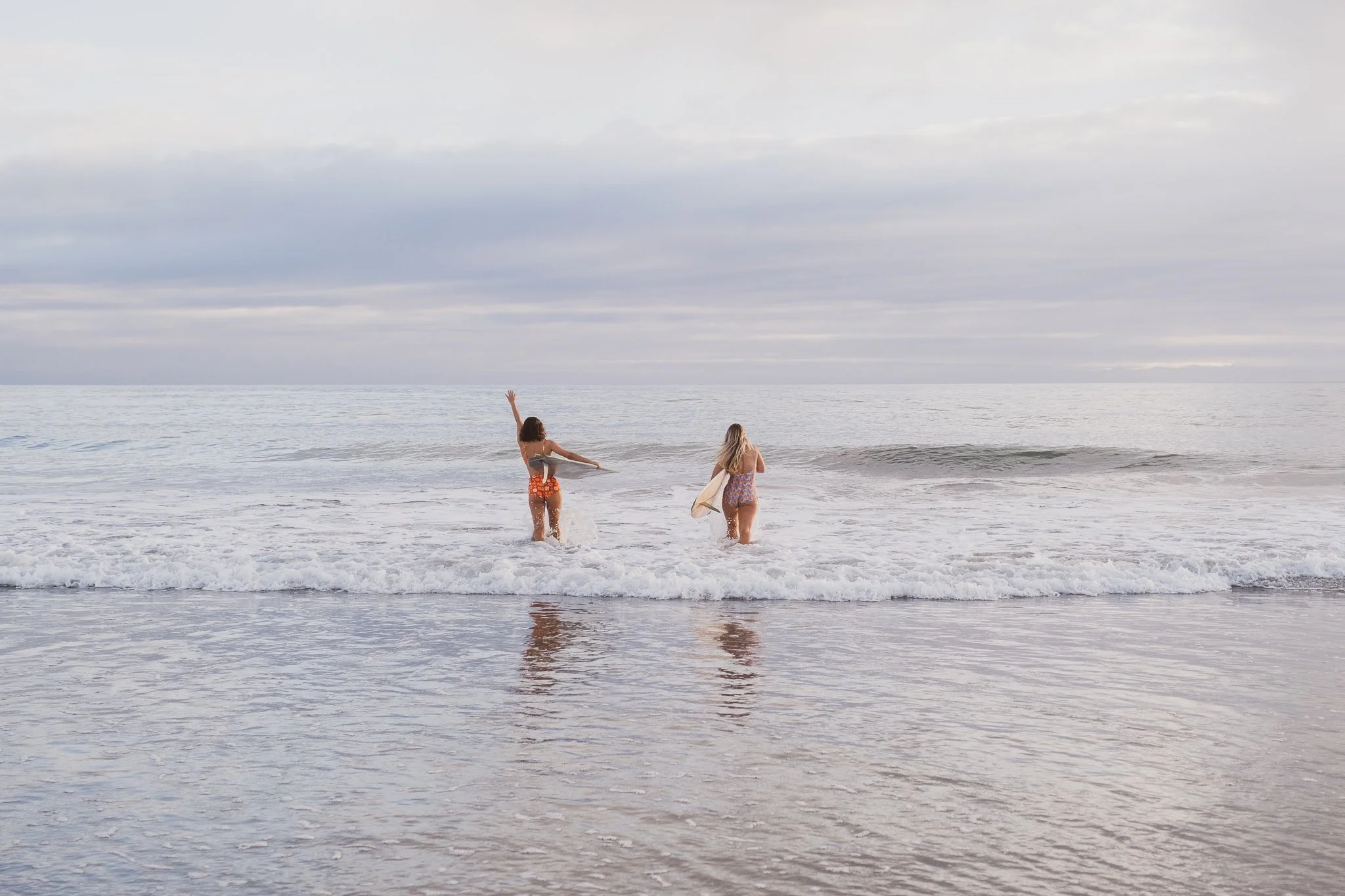 two surfers walking into shoreline together during Nostalgic Surf styled surf photography shoot lifestyle storytelling transition moment beach campaign imagery