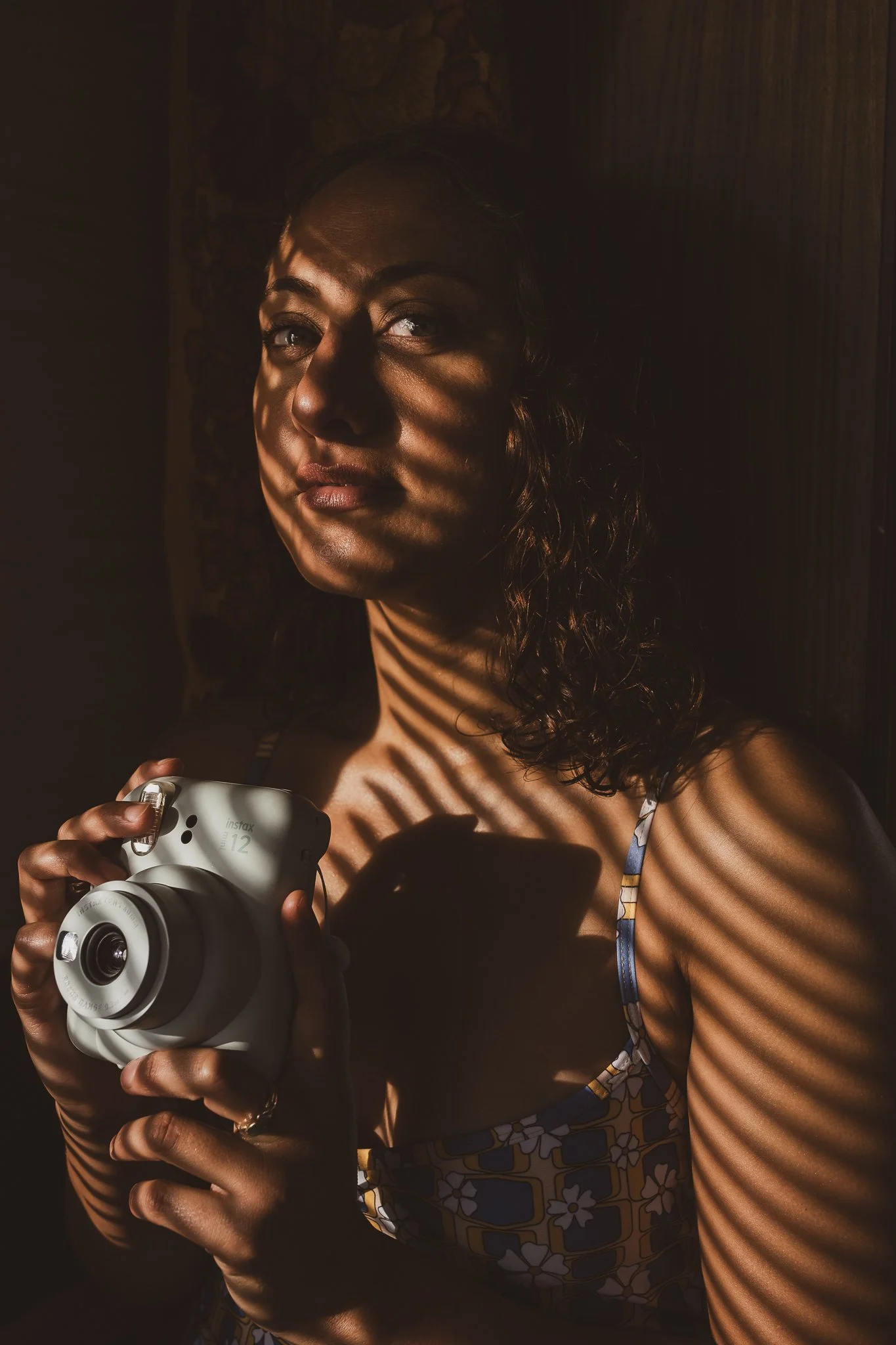 close up portrait of model holding Fujifilm Instax camera inside vintage caravan during Nostalgic Surf styled surf photography shoot retro storytelling detail