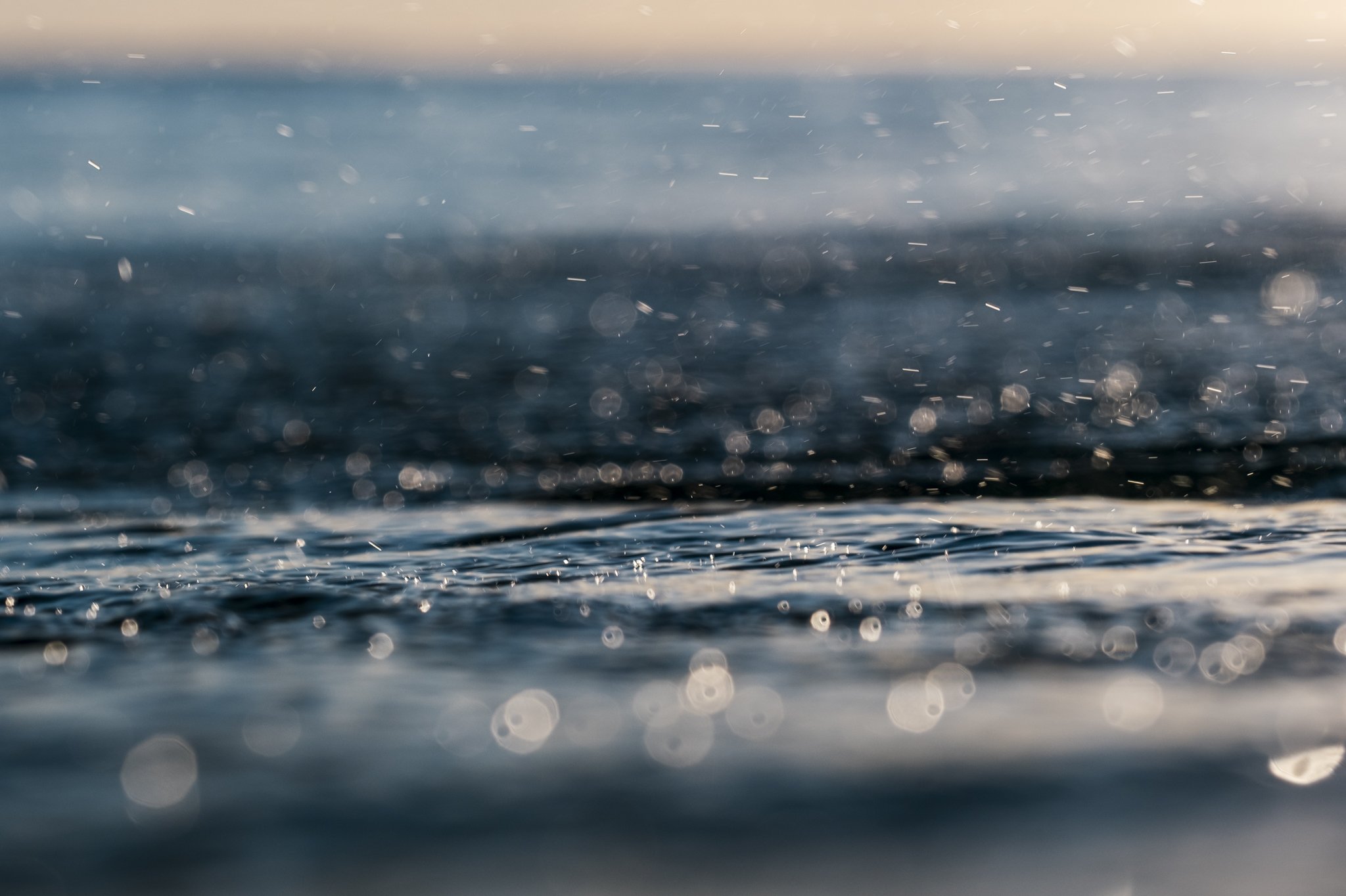 Close-up ocean surface reflections and water droplets photographed at water level for surf photography