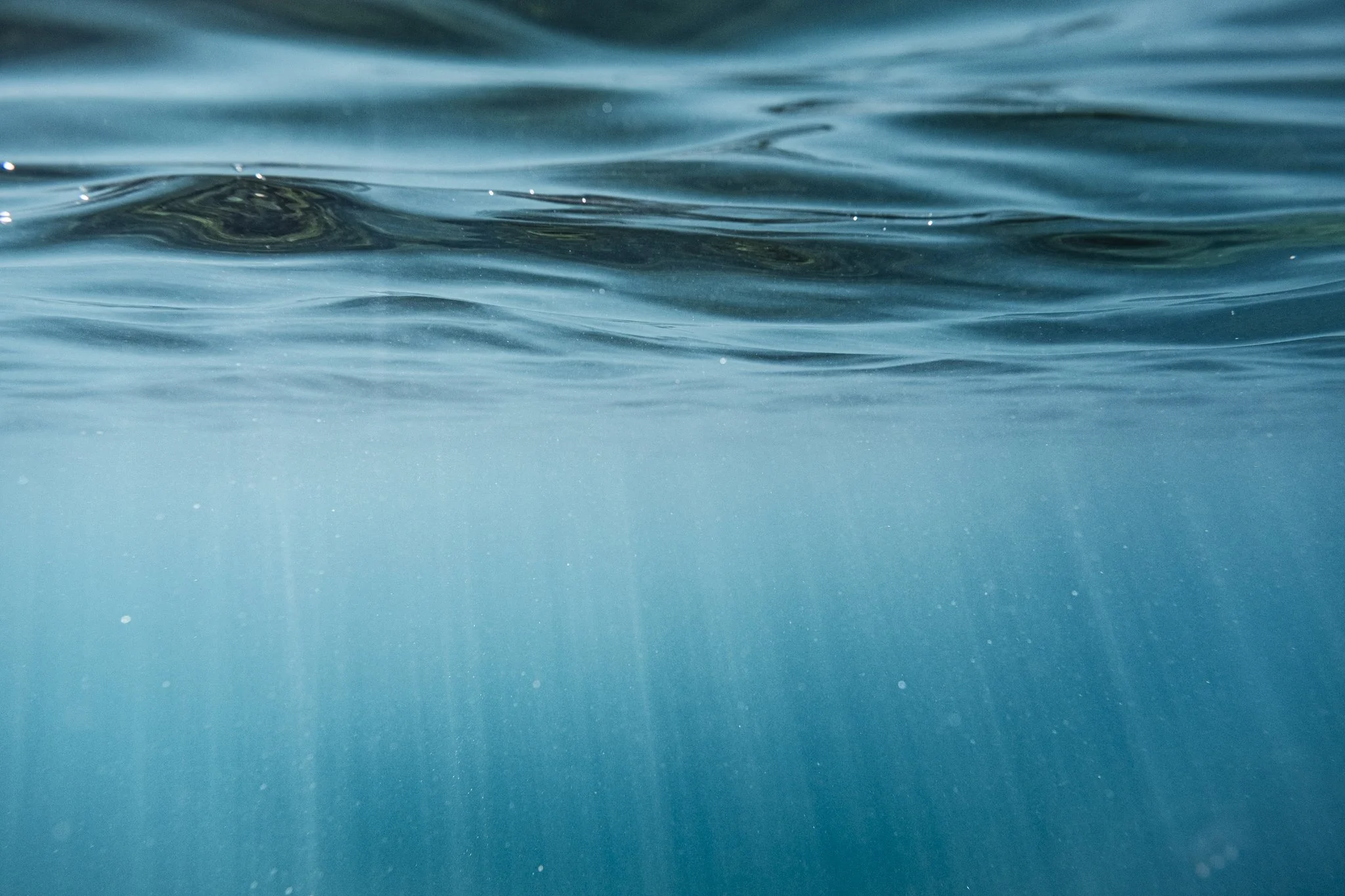 Underwater view looking up at ocean surface light rays captured while swimming with a surf photography housing