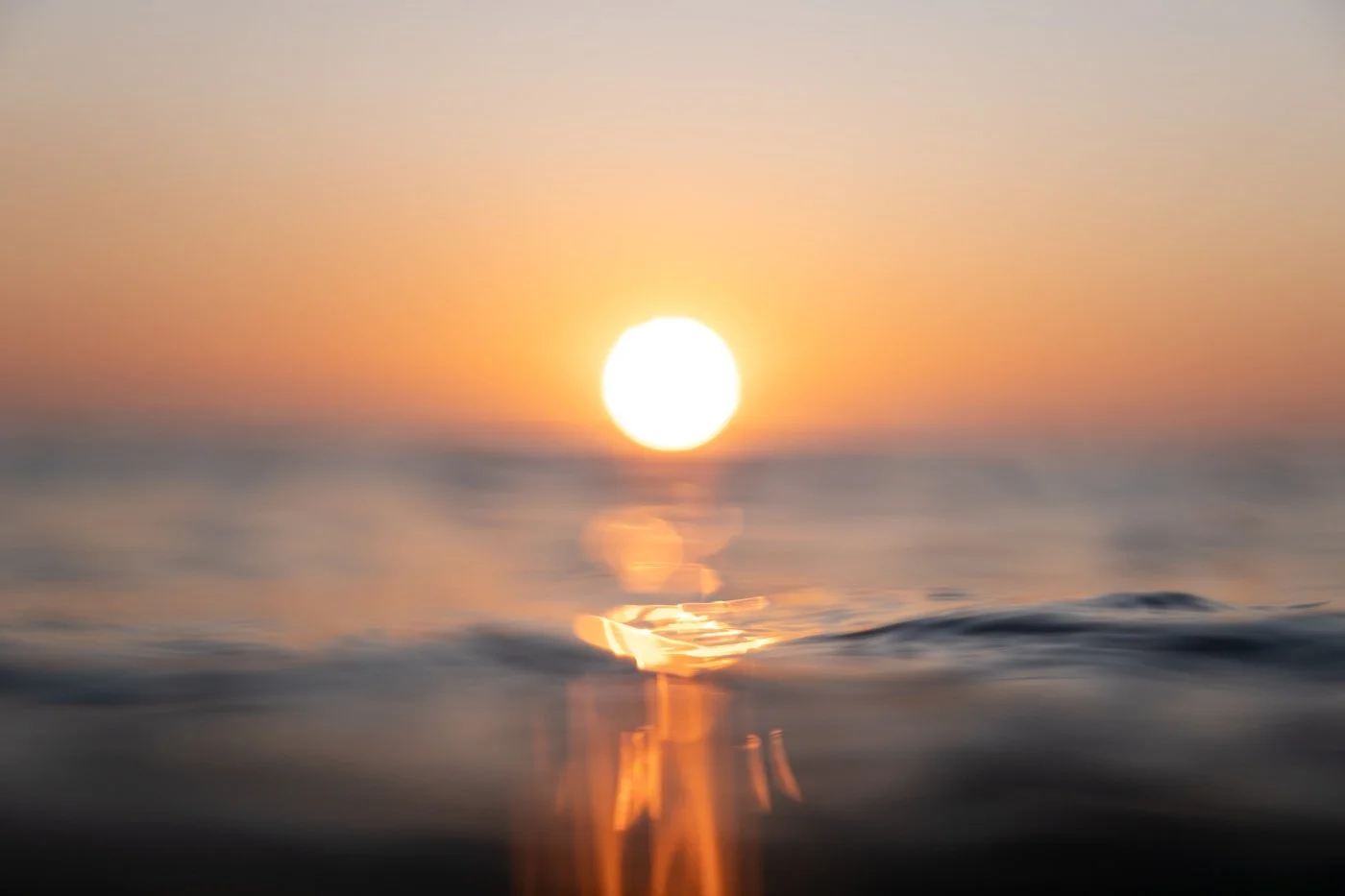 Sunrise viewed from sea level at Mount Maunganui with glowing reflection across calm morning water
