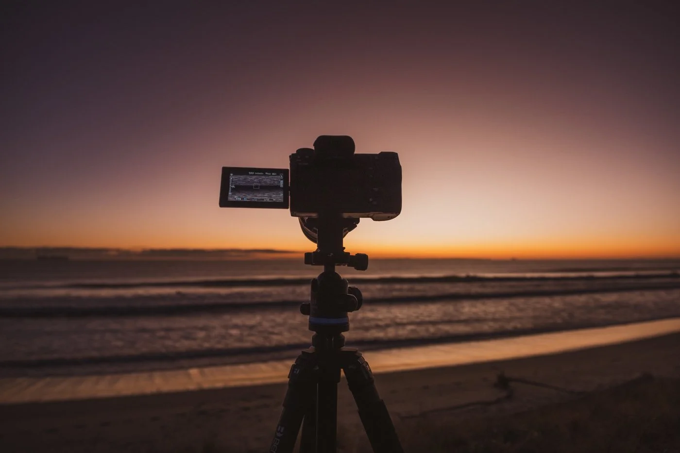 Camera on a tripod above the beach dunes at sunset, set up for coastal photography