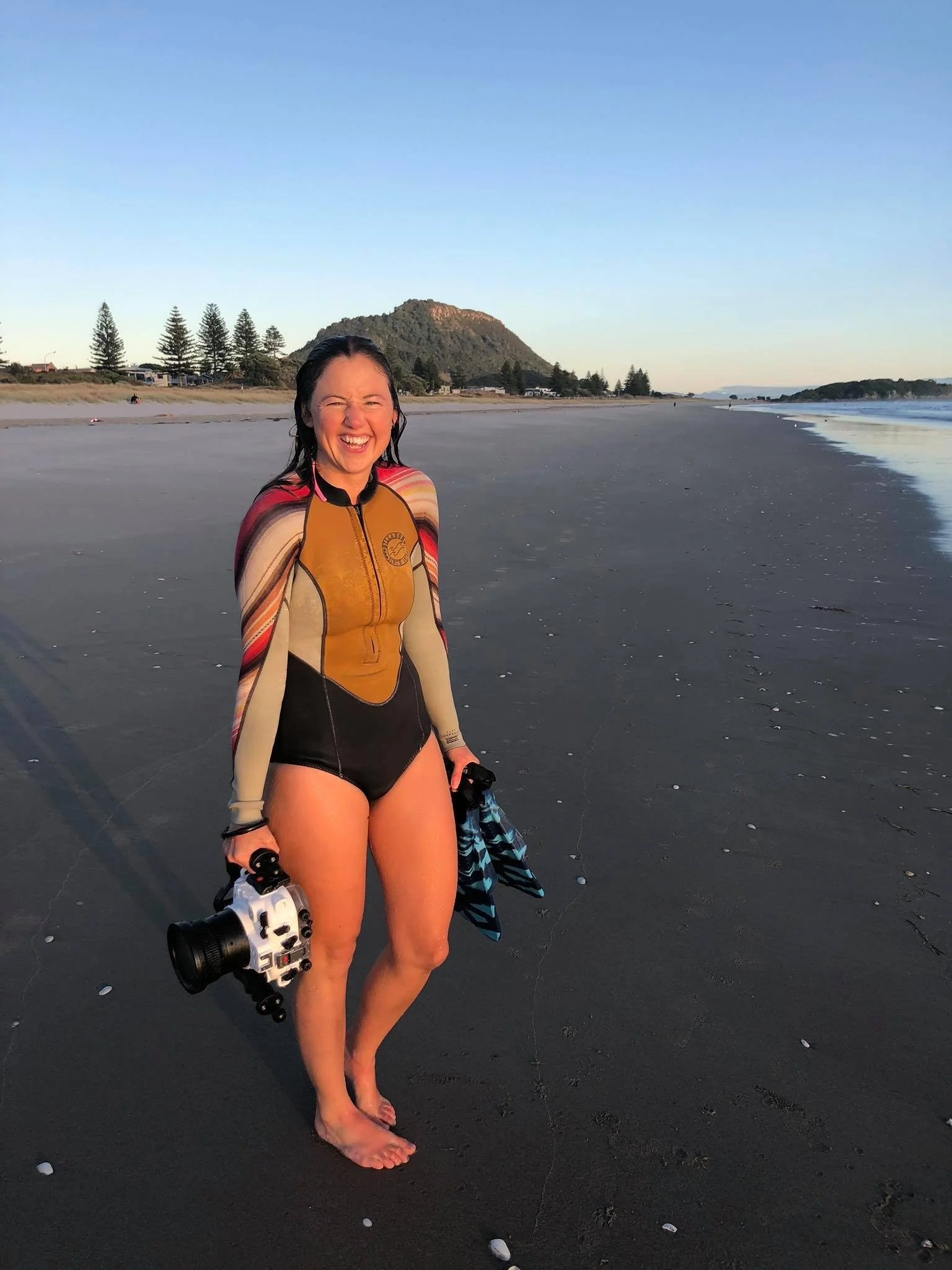 Surf photographer walking along the beach holding a waterproof camera housing after an ocean photography session