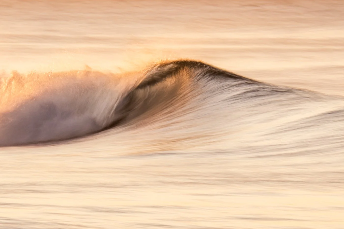 Golden wave lip captured with slower shutter speed creating soft motion blur in the water.
