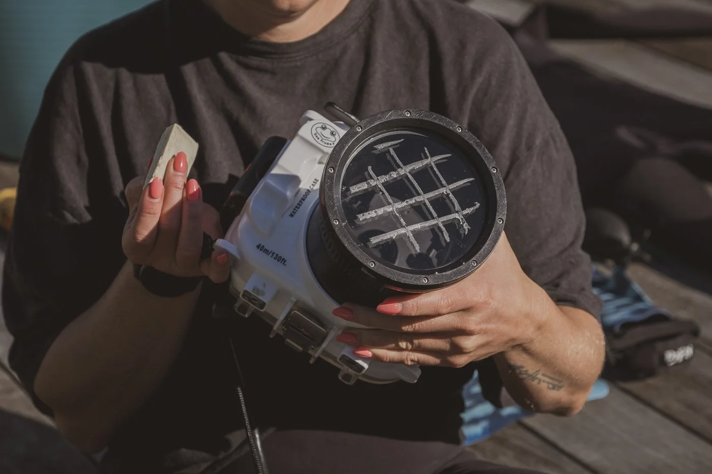 Close-up of surf wax applied in a cross-hatch pattern to a waterproof camera housing flat port.