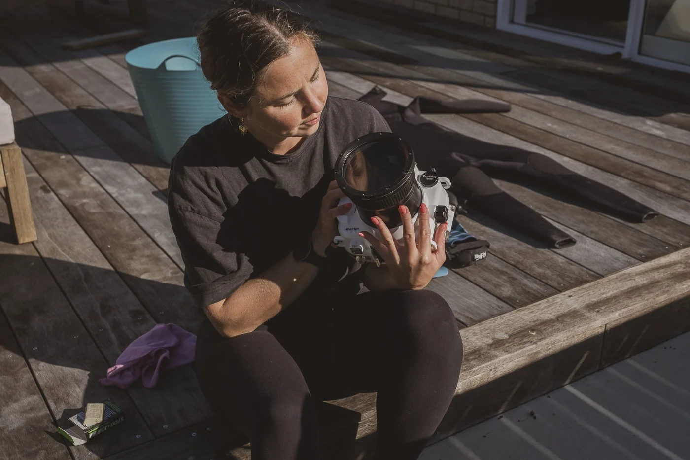 Photographer holding a waterproof camera housing while preparing the flat port for an in-water surf photography session.