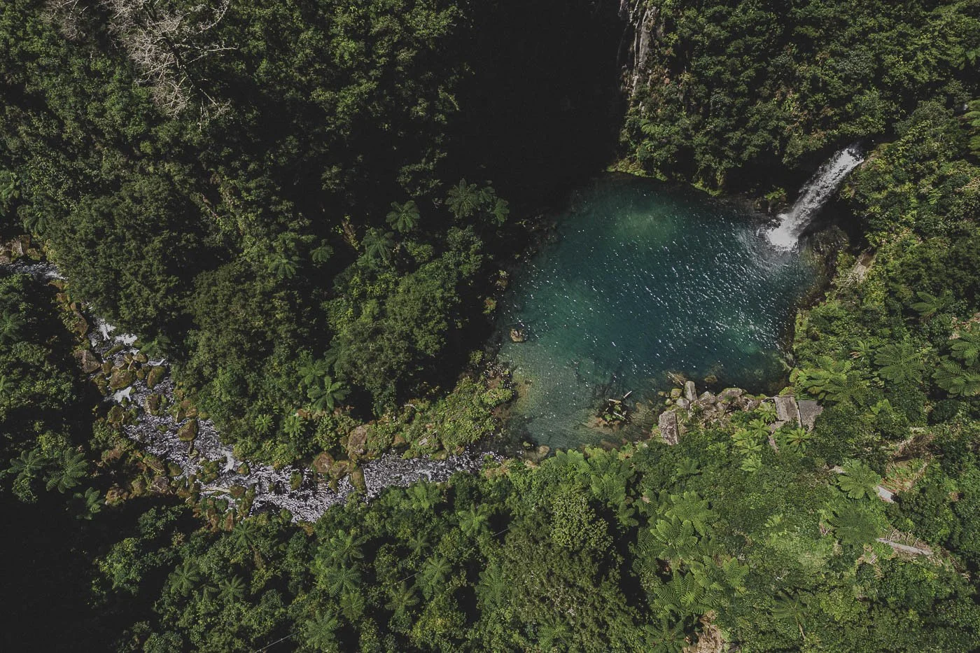 Aerial view of the turquoise pool and waterfall at Te Rere o Ōmanawa near Tauranga