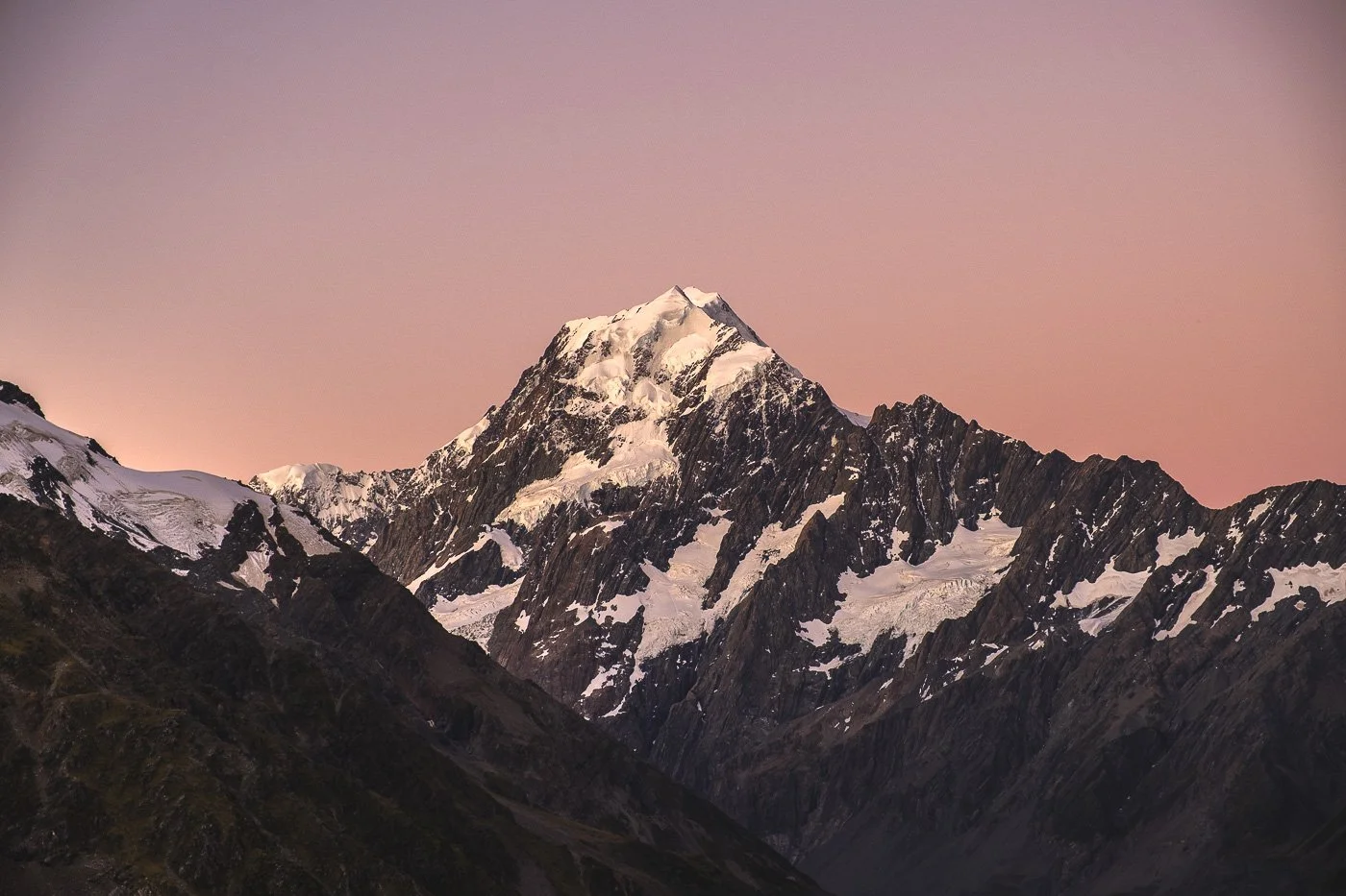 Aoraki / Mount Cook glowing beneath a pink sunset sky in Aoraki / Mount Cook National Park.