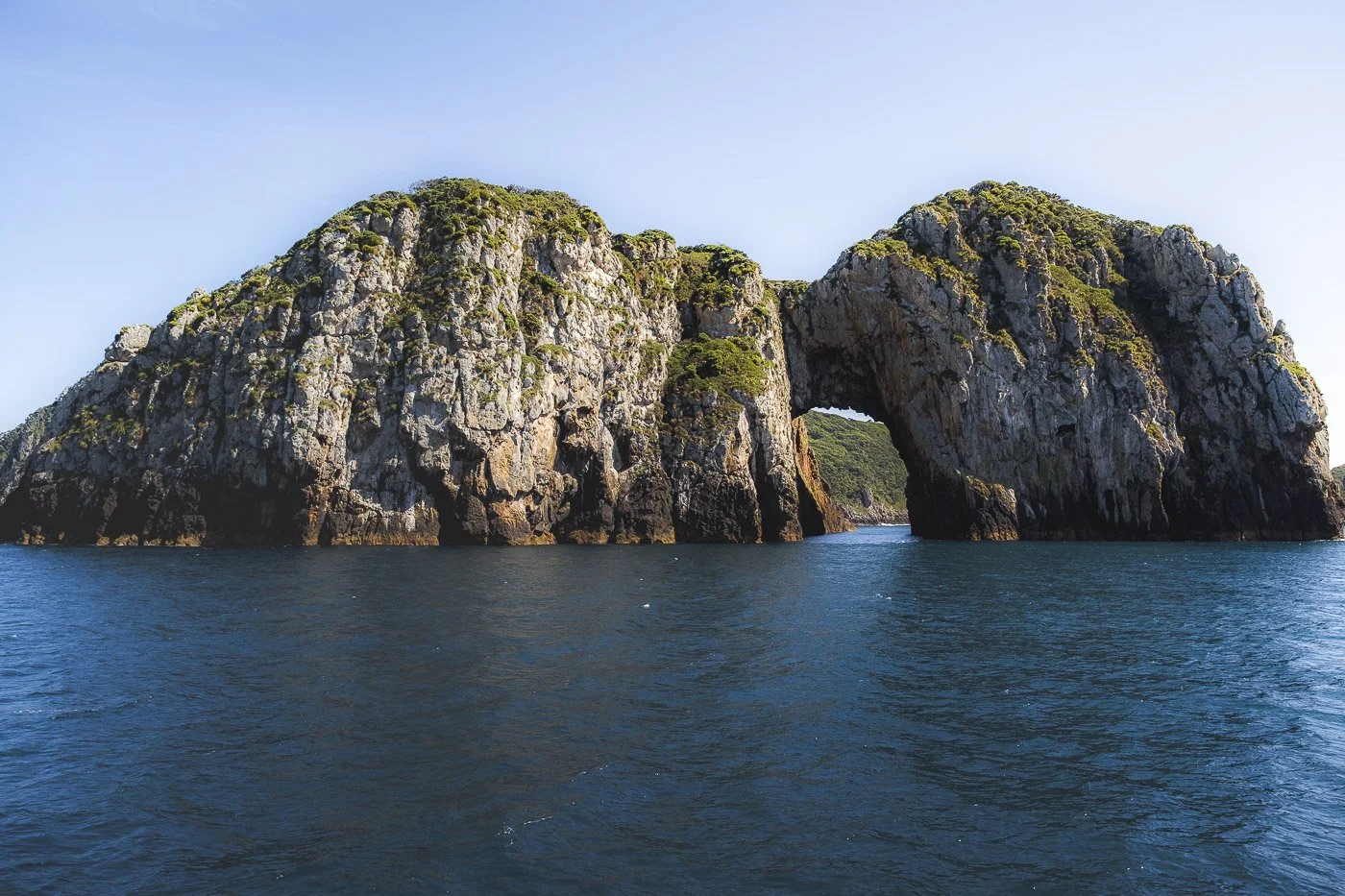 Rocky cliffs and natural arch at the Poor Knights Islands marine reserve in Northland, New Zealand
