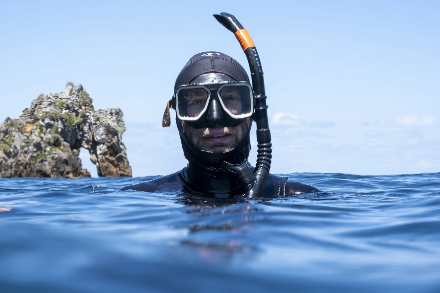 Snorkeller in the ocean beside the rocky coastline of the Poor Knights Islands, New Zealand