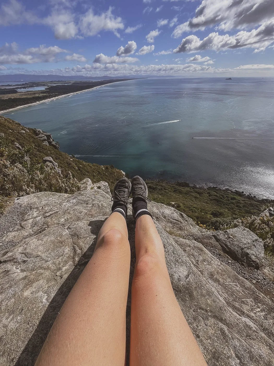 Looking out over Mount Maunganui's coastline and harbour from a rocky viewpoint near the summit of Mauao.