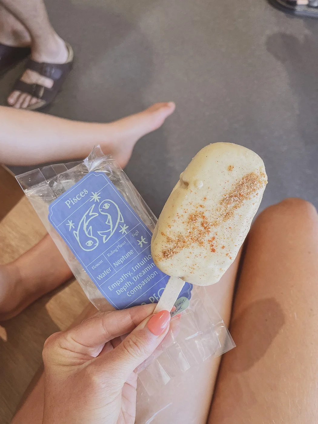 Hand holding a creamy ice block and its blue packaging while relaxing on a sunny day.