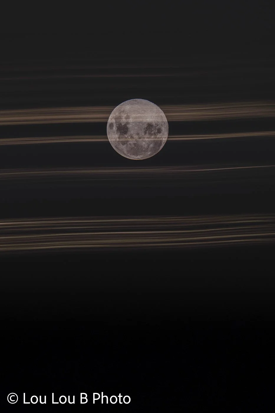 Abstract photo of full moon framed by horizontal streaks of light against a dark night sky.