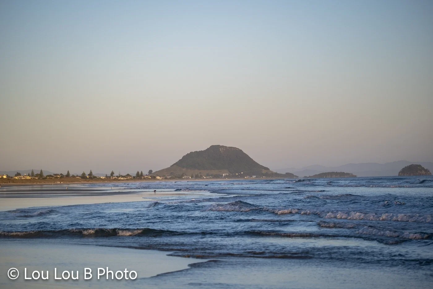 Mauao viewed across Mount Maunganui beach and shoreline in soft morning light