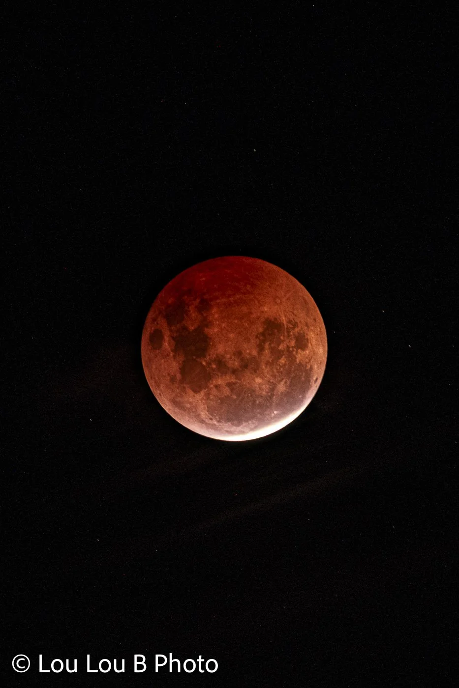 Blood moon lunar eclipse glowing deep red against a black night sky.