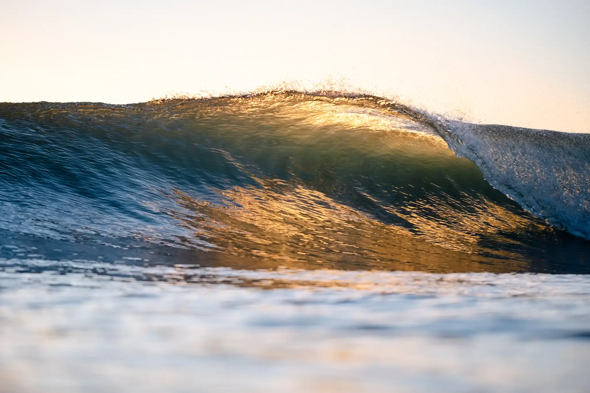 Sunlight glowing through the lip of a breaking wave during golden hour surf photography