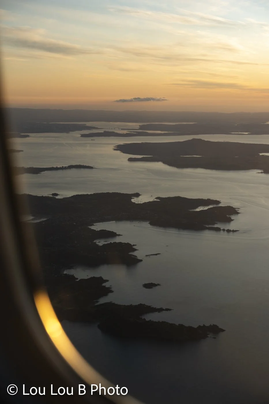 Aerial view of New Zealand coastline and islands at sunset from an aeroplane
