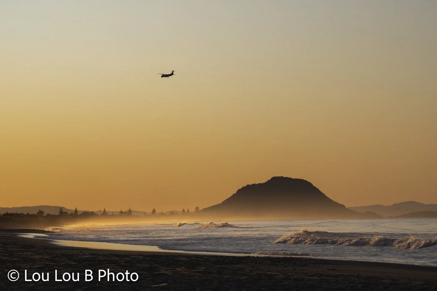 Mauao and Mount Maunganui beach in golden light with a Air New Zealand plane flying overhead