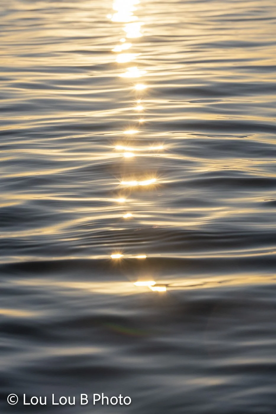 Vertical view of sunlight sparkling across gently rippled ocean water.