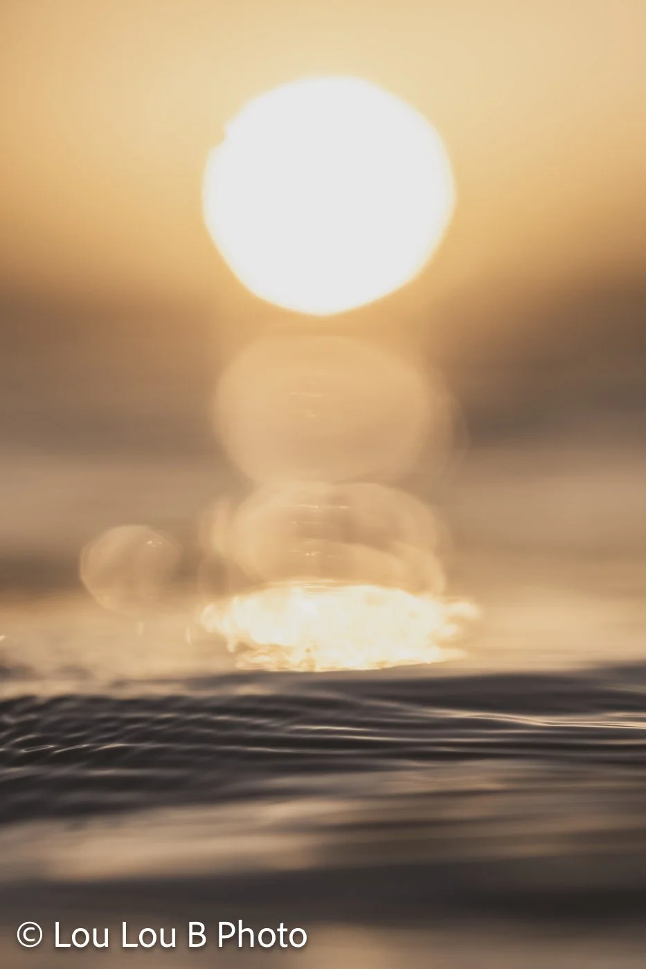Abstract golden sun and reflection glowing above dark ocean ripples.