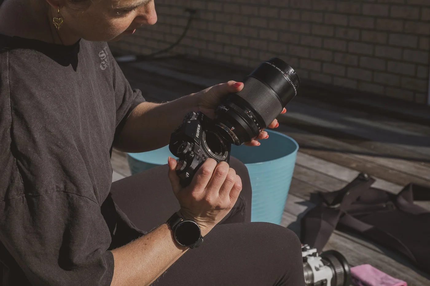 Photographer attaching a prime lens to a Fujifilm camera before setting up an underwater camera housing.