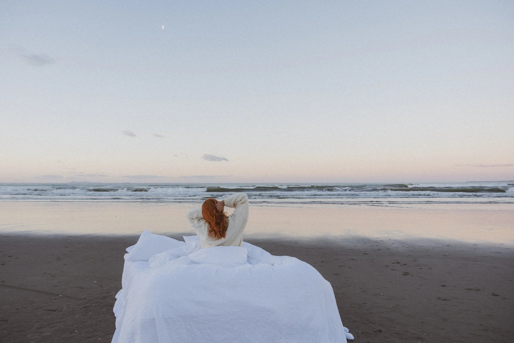 Lifestyle photography commission of a bed on a New Zealand beach at sunset.