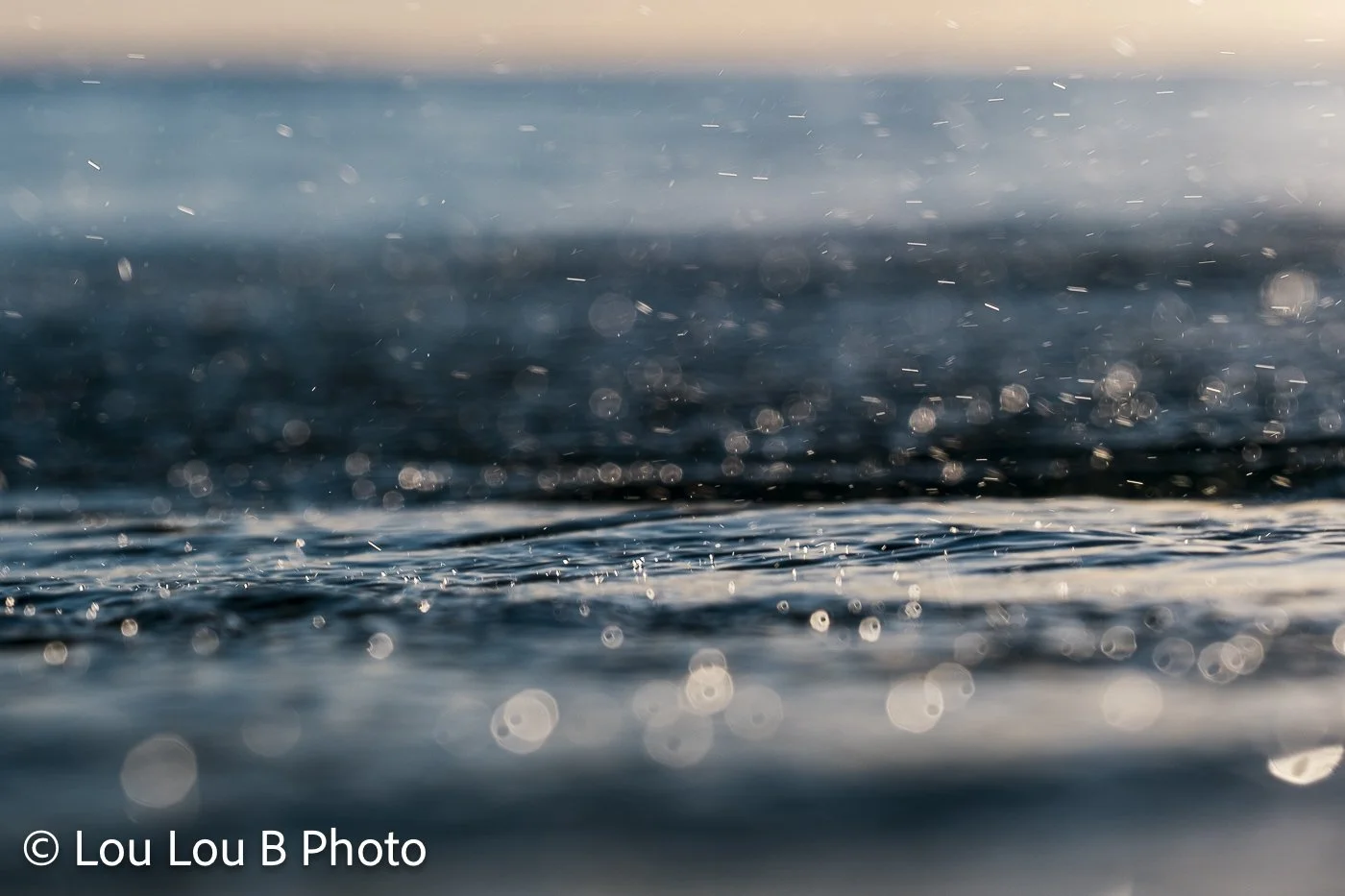 Close-up water-level view of sea spray and droplets suspended above the surface of the ocean.