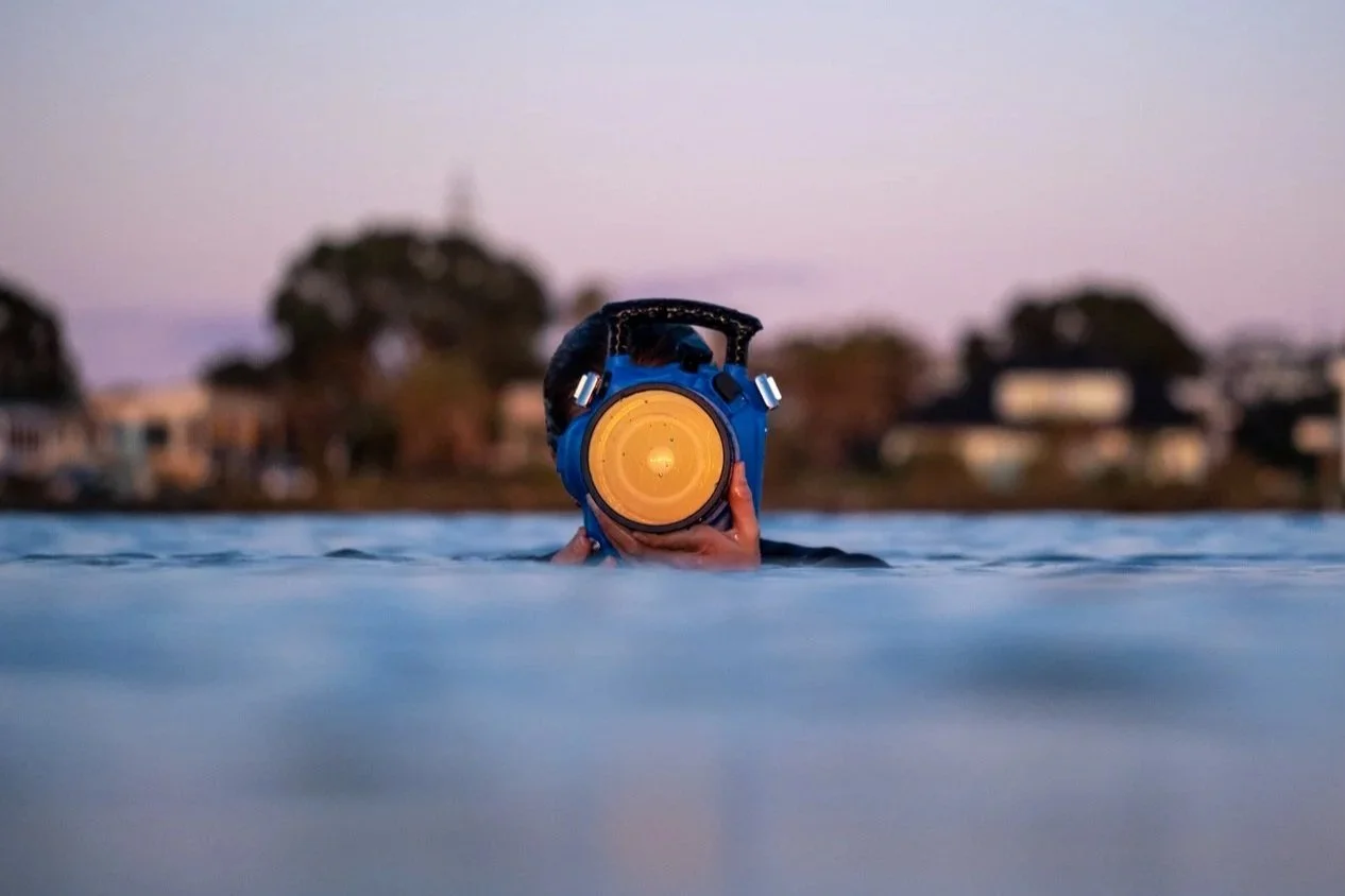 Surf photographer shooting from the ocean surface using a professional surf photography water housing at sunrise.