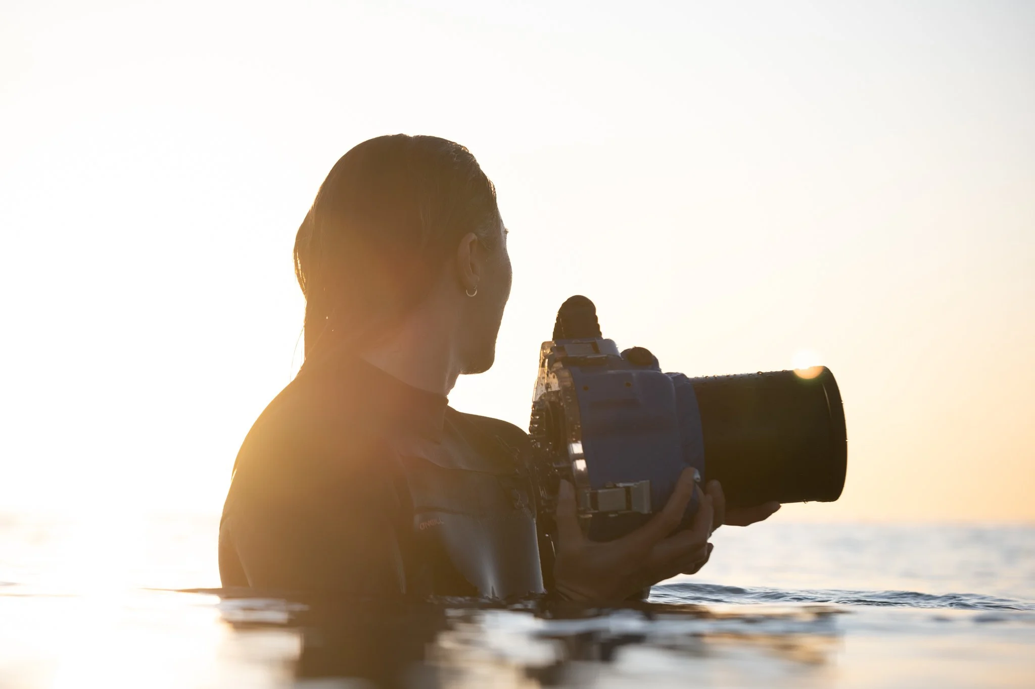 surf photographer using water housing in the ocean during golden hour surf photography session