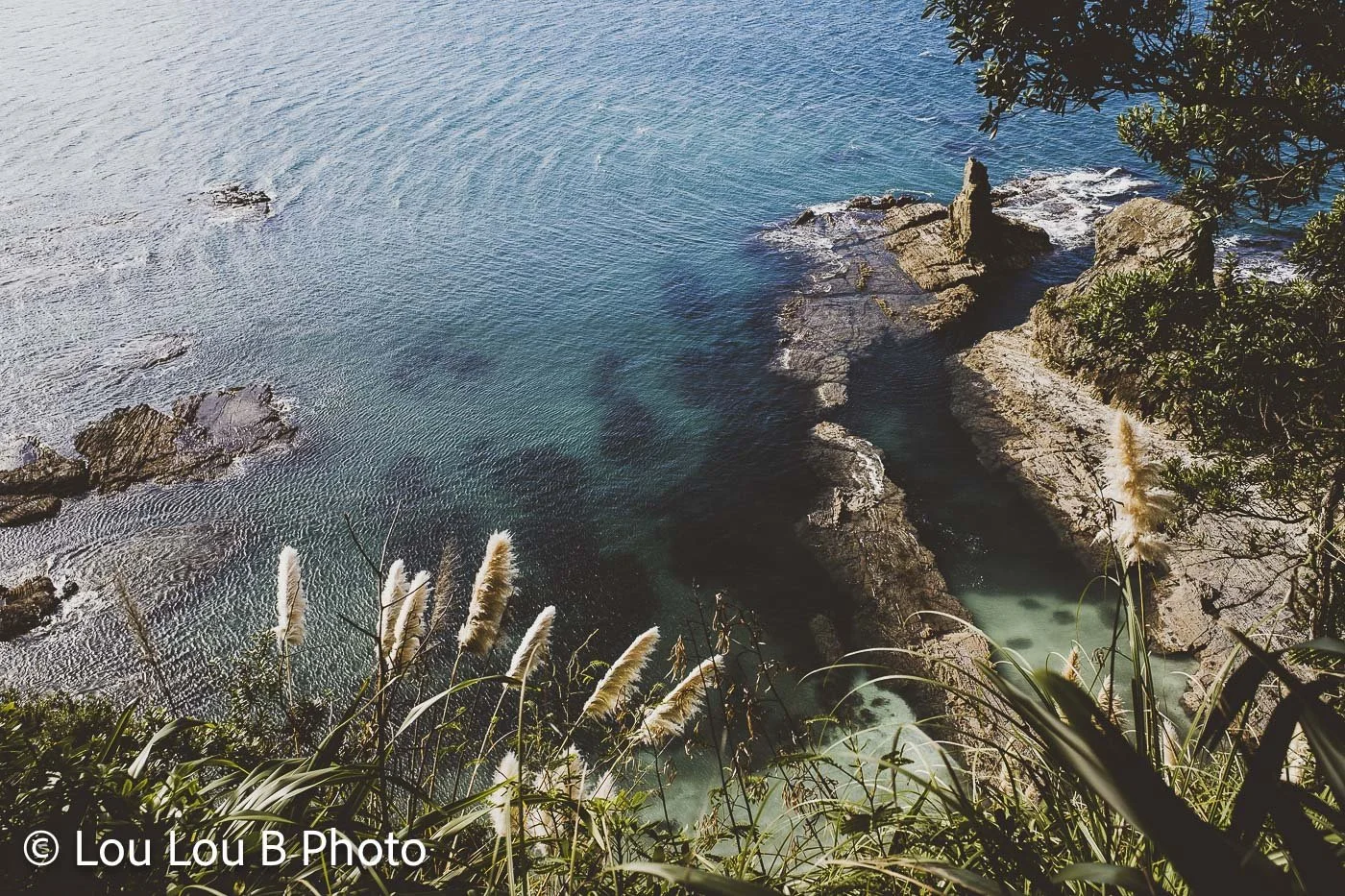 Rocky coastal cove surrounded by clear blue and turquoise water.