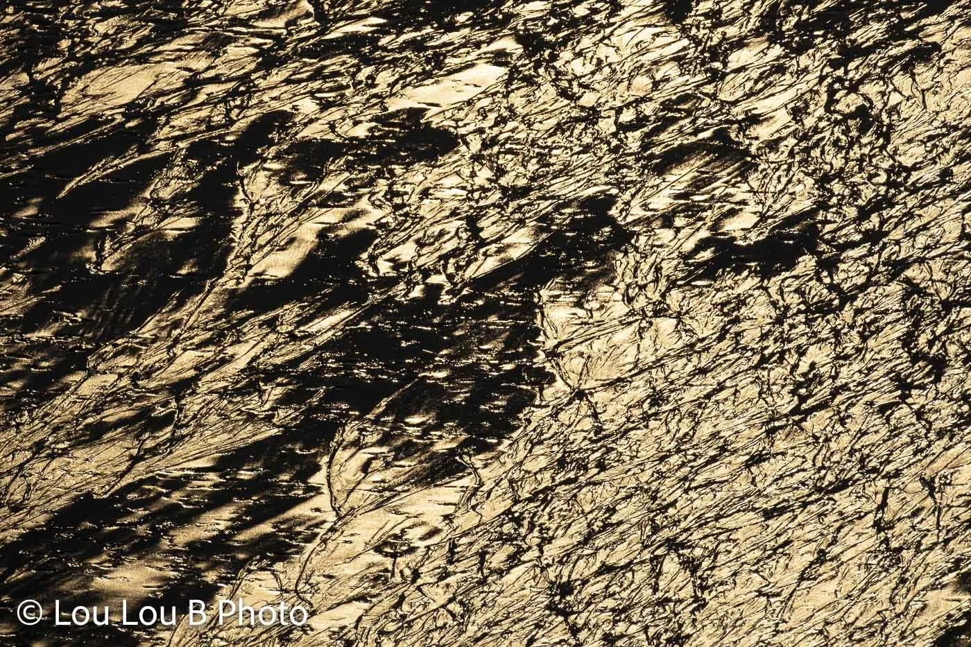 Abstract close-up of textured ocean water reflecting rich golden sunlight.