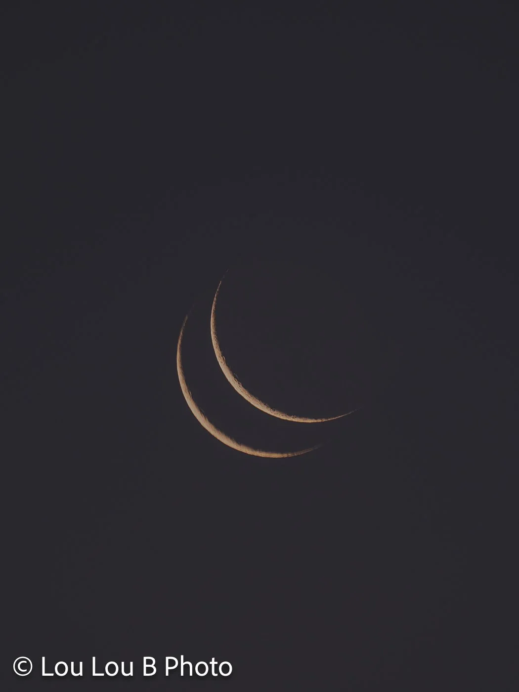 Abstract double crescent moon created through intentional camera movement against a dark sky.
