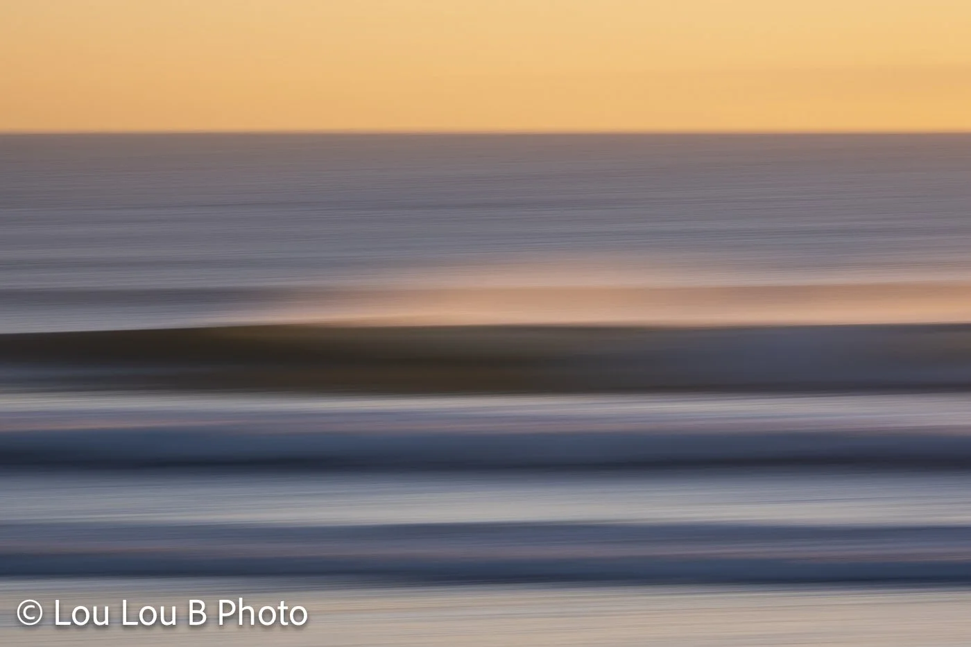 Abstract long-exposure seascape with blurred bands of ocean beneath a warm golden horizon.