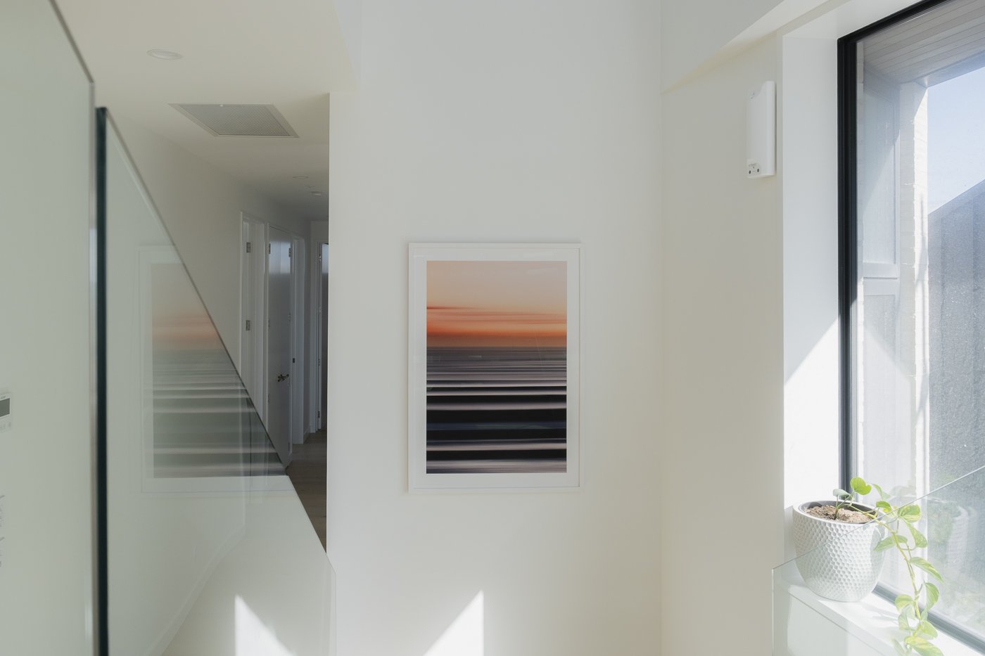 A1 framed coastal photography print with white mat board displayed on staircase wall in modern beach house interior