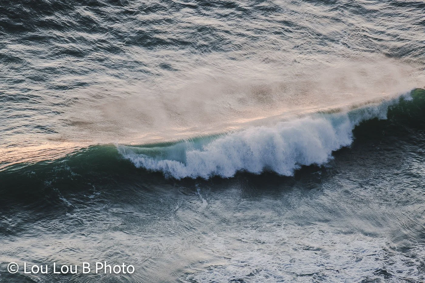 Breaking ocean wave with turquoise-green water and white sea spray.