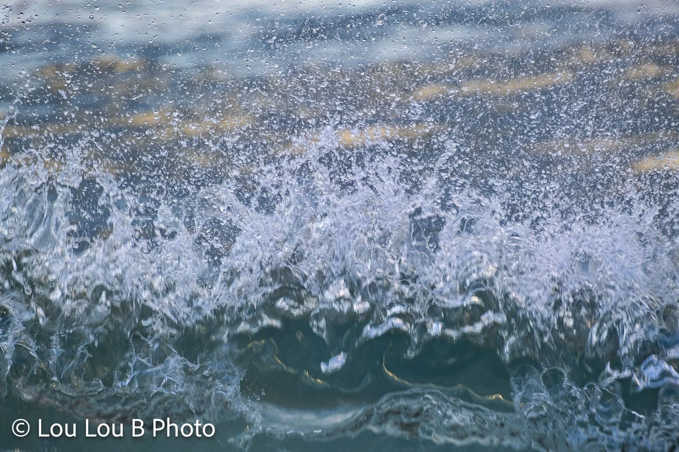 Close-up of a breaking turquoise-blue wave filled with sparkling sea spray.